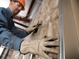 Contractor installing fiberglass batt insulation
